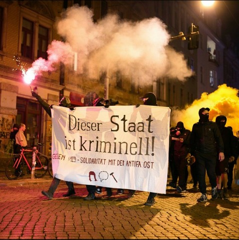 Foto von einer Demo, zu sehen ist ein Front Transpi auf dem steht: 
Dieser Staat ist kriminell - Solidarität mit der Antifa Ost