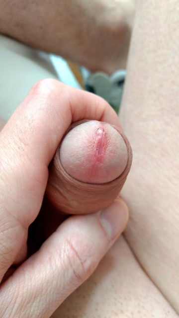 Close in shot of my soft penis while I grasp it with my fingers. Foreskin almost fully retracted revealing my dick's head with precum droplet