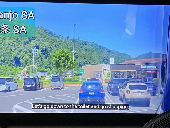 Still photograph from a travel video from Japan.

Picture: the car park in a motorway service area.

Closed caption at the bottom of the screen:

