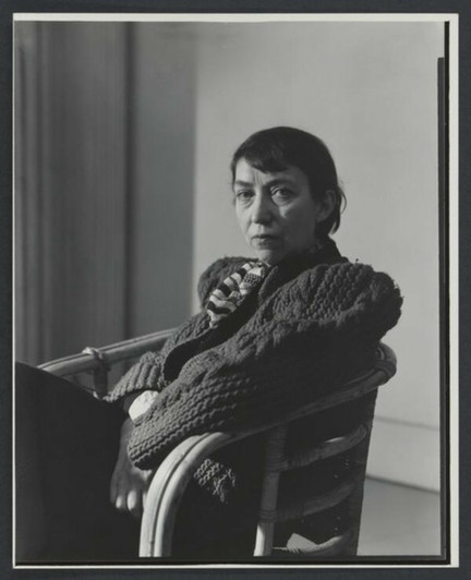 Portrait of Berenice Abbott seated at a chair turned to the left with her head turned halfway towards the camera and looking straight into the lens 