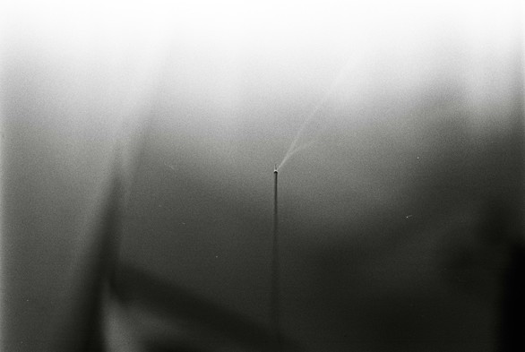 A black and white image of a piece of incense lit.