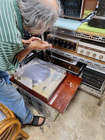 Ein älterer Verkäufer schließt einen Luxman Plattenspieler an weirde Verstärker an.
