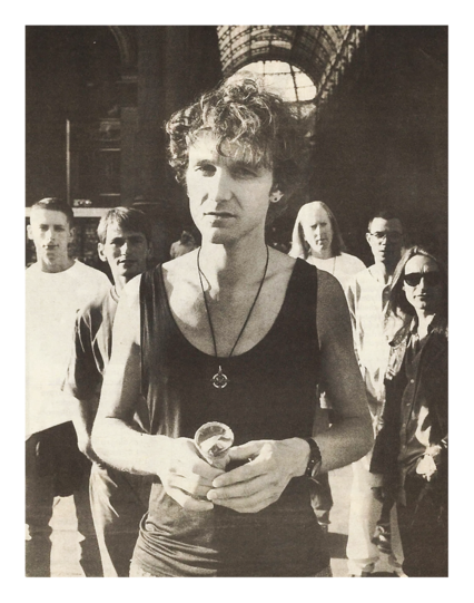 sepia newsprint scan. outdoors. tim booth in the foreground, the other members in the background. all making eye contact.