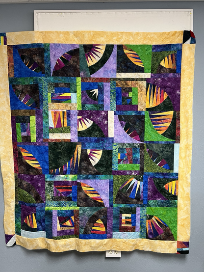 Brightly colored quilt made of curved paper-pieced blocks and random scraps. Bordered in bright yellow. 