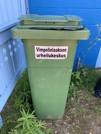 A green trash bin with a label that reads 