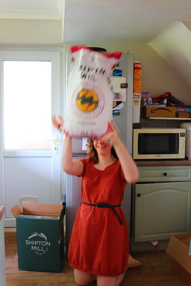 It's me again, once again in a red dress but this time kneeling on the kitchen floor and lifting the sack of flour above my head. The photo is an action shot: I'm not strong enough to hold it there!