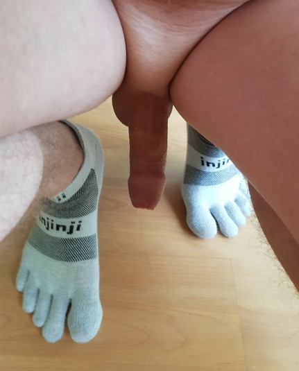 frontal photo of my soft penis and feet where I have my knees bent and am wearing grey Injinji toesocks