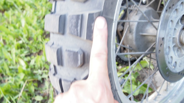 finger points to knobby motorcycle tire 'chicken-line'