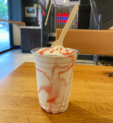 A large vanilla Frosty with strawberry sauce, at a table in a Wendy’s in London