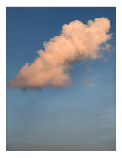 a large, oblong cloud with orange tint hangs at an angle in a gray blue sky. faint cloud streaks below.