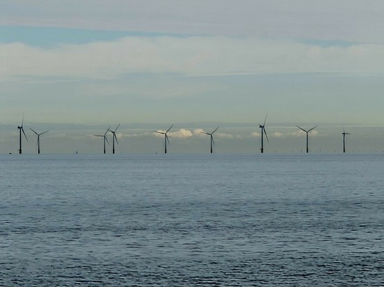 View over the sea, with wind turbines in the distance. 