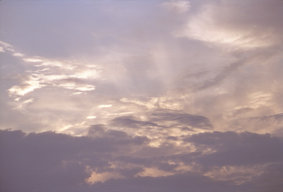 A glowing cloudscape with blue and purple hues as well as the yellow touches of the sun. 