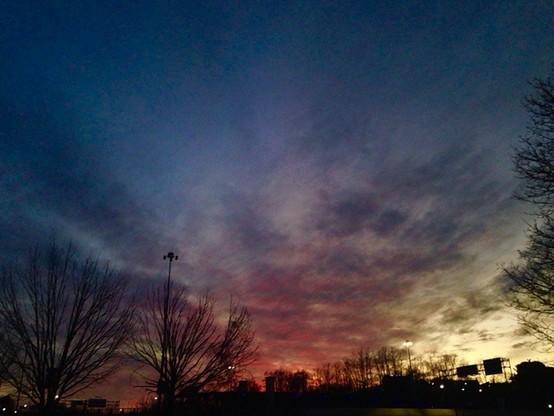 Color image of a spectacular sunset in Akron, Summit County, Ohio, USA.  Image shows trees having lost their leaves during autumn, with the lower angle of the sun bringing on spectacular hues of oranges, reds, blues, greens, purples and yellows.