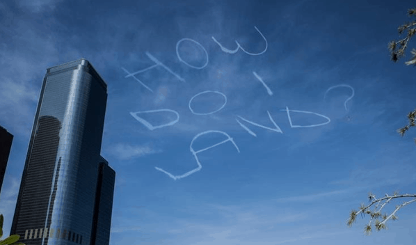 Picture of blue sky with skywriting that says “HOW DO I LAND?”