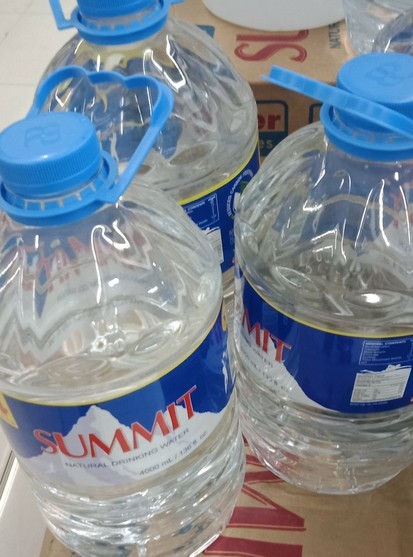 large plastic bottles of Summit Natural Drinking Water. The bottles are clear and filled with water.