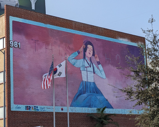 Mural of a woman with physical US and Korean flags in front