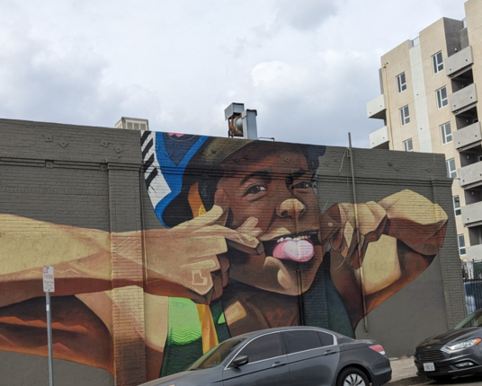 Mural of a kid pulling their mouth open and sticking out their tongue.
