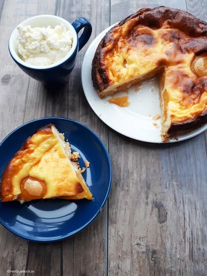 Holzuntergrund. Darauf eine kleine Platte mit einem angeschnittenen Aprikosen-Käse-Tarte. Daneben ein Teller mit einem Stück davon. Habt ein schönes Wochenende:-)