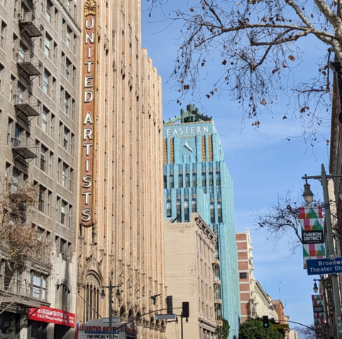 Vivid blue skyscraper with Eastern on the top and a clock with a tall United Artists sign in the foreground