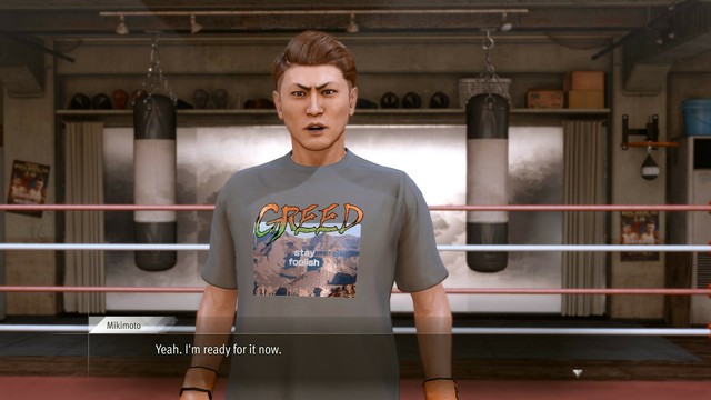 A screenshot from the video game Lost Judgement.

A man stands in a boxing ring wearing a grey-tan T-shirt that says "GREED" in all caps in a rough font and orange to green color gradient. Underneath "GREED" there is what looks like a low resolution stock photo of desert mountains. Across the stock photo are the words "stay foolish" in all lowercase, in a different font, in plain white coloring.

It's an absolutely ridiculous shirt.