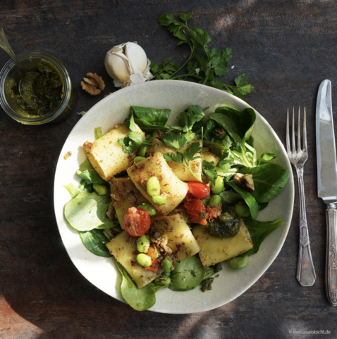 Dunkelbrauner Untergrund. Darauf ein weißer Pastateller mit Nudeln auf Feldsalat - mit Tomaten, Edamame (Das sind junge grüne Sojabohnen) und Petersilienpesto.
Dunkelbrauner Untergrund. Darauf ein weißer Pastateller mit 