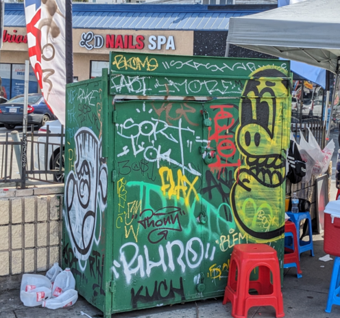 Graffitied dumpster with a prominent bean shaped face