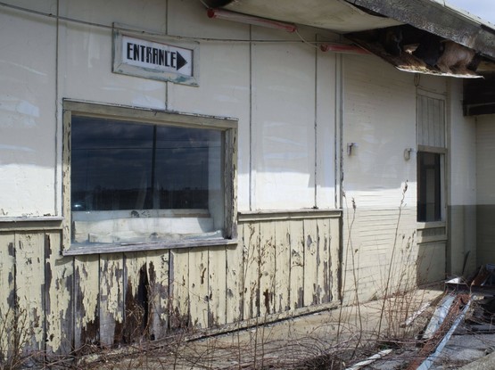A sign reading "entrance" is affixed to an abandoned building.