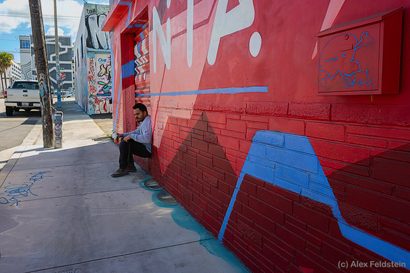 A guy sitting down and having a soda on the street in Wynwood, the colorful mural district in Miami