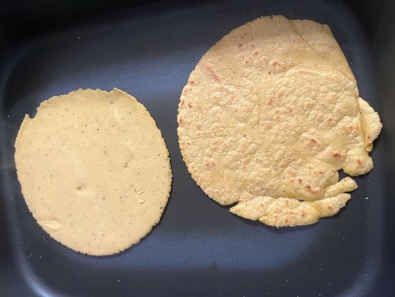 Two types of flatbreads (tortillas) are positioned on a flat surface. The left one is round and slightly thicker, while the right one is larger, thinner, and has uneven edges.