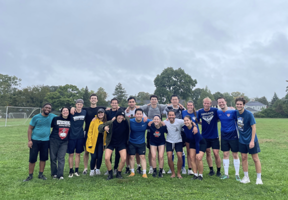 A group of grad students in sports wear on a soccer field. 