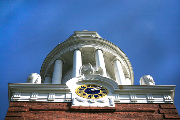 A steeple with a clock seen from a low angle.