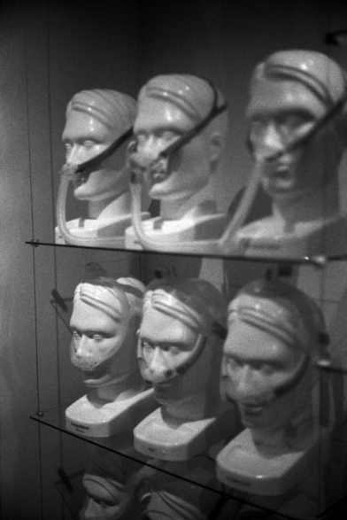 A black and white photograph depicting a display of CPAP masks on identical dummy heads.  