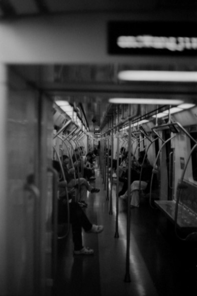 Lucky SHD 400

**English:**
A black-and-white photograph of the interior of a subway train. The image captures passengers seated and standing, holding onto handrails and poles. The train is in motion, and the lighting is dim, creating a somewhat blurred effect due to the movement.

**Chinese:**
一张地铁车厢内部的黑白照片。照片中乘客们有的坐着，有的站着，手扶着扶手和立柱。地铁正在行驶中，灯光昏暗，由于运动产生了一些模糊效果。