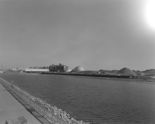 A black and white photograph of the shrouded bridge and pods of Ontario Place and the utter ruin of the West Island. 