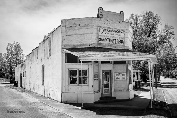 Small thrift store on a triangular lot next to railroad tracks.
