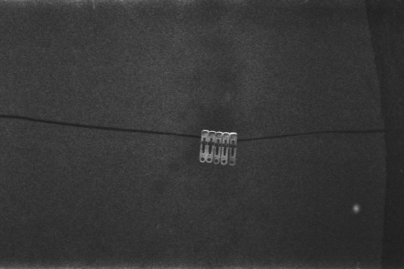 **English Alt Text:**
This image shows a close-up of a dark fabric surface with a small, metallic object attached to it. The object appears to be a set of small, connected metal loops or clips, possibly used for fastening or decorative purposes. The fabric has a slight texture, and the lighting highlights the metallic sheen of the object.

**Chinese Alt Text:**
这张图片展示了深色织物表面的特写，上面附着一个小金属物体。该物体看起来是一组小的连接金属环或夹子，可能用于固定或装饰目的。织物略带纹理，灯光突出了金属物体的光泽。