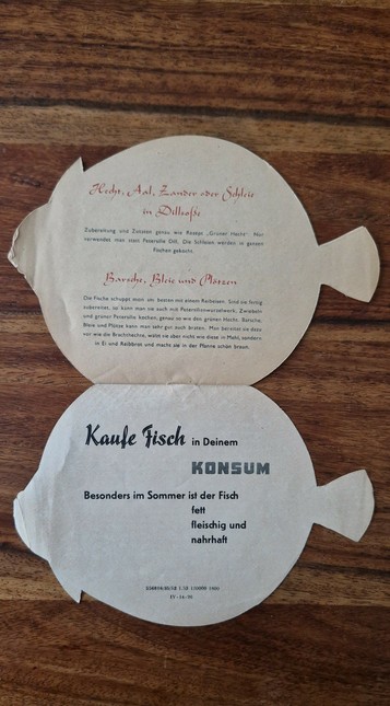 A spread from the back of the fish-shaped leaflet. It offers general tips for preparing fish and promotes fish consumption with socialist slogans. Simple recipes like “Hecht in Dillsoße” and fried perch are included, ending with a call to buy fish at your local Konsum store.