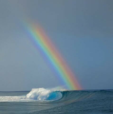 A rainbow over ocean breaking waves.