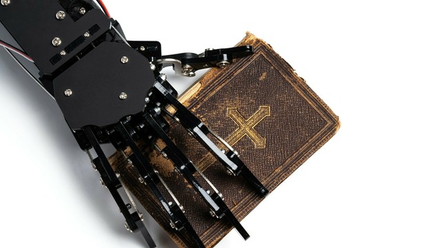 A robot hand holding an old Christian Bible.