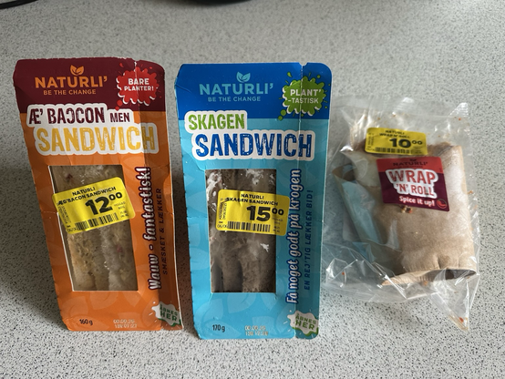 Two different boxes of sandwiches and a package of wraps from the company Naturli'. The first sandwich is called "Æ' baccon men sandwich" which is a play on the words "egg and bacon" in danish, spelled so that it sounds like "not bacon but sandwich" in a dialect of danish. The other is called Skagen Sandwich, after the city of Skagen, and I assume it’s some kind of vegan fish or shrimp sandwich.