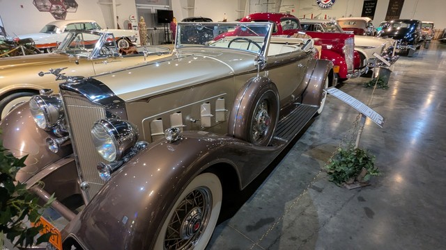 A large vintage automobile circa 1936. It is a convertible with two tone paint, brown fenders with a tan body.