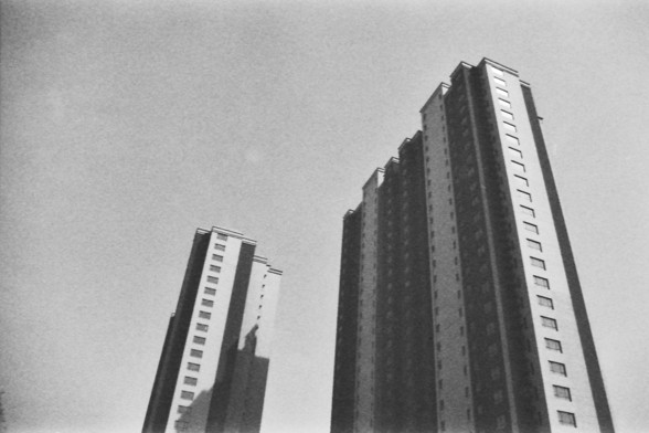 Ilford FP4 @ ISO 64

**English alt text:** The image shows two tall, rectangular buildings with multiple windows, captured in black and white. The buildings are positioned against a clear sky, with one building slightly in front of the other.

**Chinese alt text:** 这张图片展示了两栋高大的矩形建筑，建筑上有多个窗户，图像是黑白的。建筑物在清晰的天空背景下，一栋建筑稍微在另一栋建筑前面。