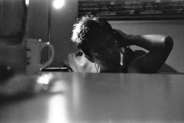 Ilford FP4 E.I. 64

**English Alt Text:**
- Description: A black-and-white photograph of a person sitting at a table. The person is leaning forward with their head resting on their hand, appearing to be in deep thought or possibly tired. There is a cup on the table in front of them, and the background is slightly blurred, focusing attention on the person. The lighting is soft, creating a reflective surface on the table.

**Chinese Alt Text:**
- 描述：一张黑白照片，照片中一个人坐在桌子旁。这个人向前倾身，头靠在手上，看起来像是在深思或者有些疲惫…
