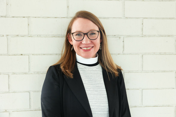 A woman in glasses and a clerical collar smiling.