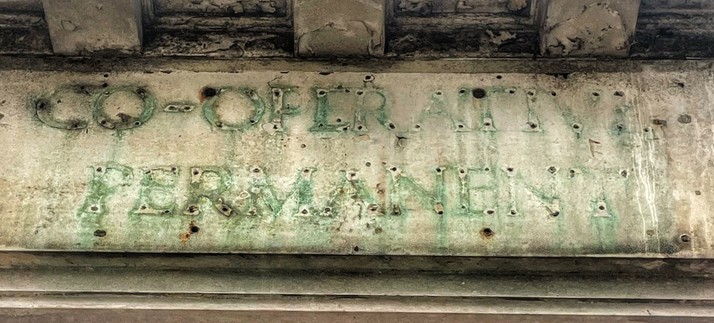 Ghost letters on stone plinth. Verdigris from old copper lettering with iron studs. Reading CO-OPERATIVE PERMANENT