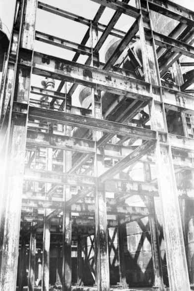 **English:**
A black and white photograph of an industrial structure, likely part of a factory or plant. The image captures the complex network of beams, pipes, and other structural components, highlighting the intricate details of industrial architecture.

**Chinese:**
一张黑白照片，拍摄的是一个工业结构，可能是工厂或工厂的一部分。这张照片展示了梁、管道和其他结构部件的复杂网络，突出了工业建筑的错综复杂的细节。