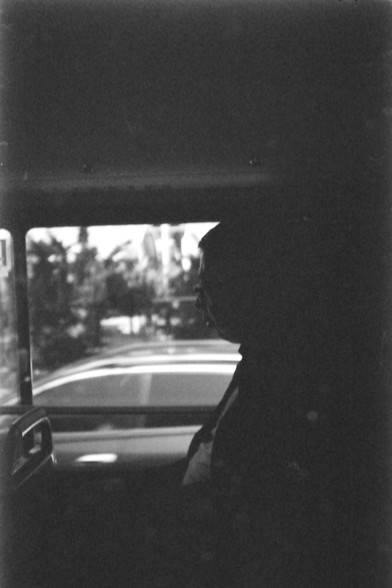 Ilford FP4 @ ISO 64

English Alt Text: A silhouetted figure sits alone inside a vehicle, gazing out of a window. The outside view is softly blurred, with hints of trees and buildings, while the interior is bathed in shadow, creating a moody black-and-white composition.

中文替代文本: 一位剪影般的人物独自坐在车内，望向窗外。窗外的景色模糊不清，隐约可见树木和建筑，车内则被阴影笼罩，构成一幅黑白对比强烈的画面。
