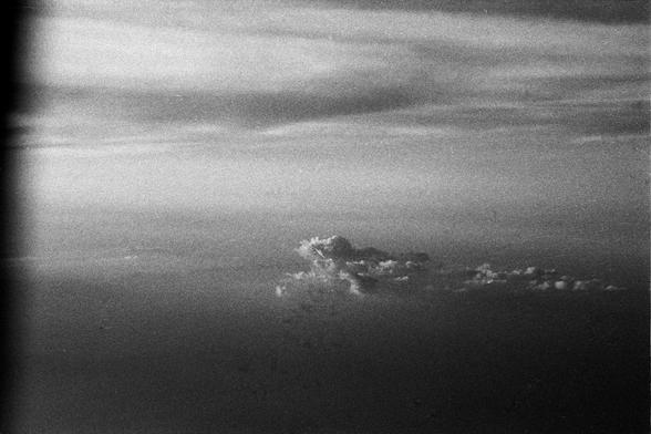 Foma FOMAPAN 400 Action (FF)

**English:**
A black and white photograph capturing the view from an airplane window. The airplane wing is prominently featured, extending from the bottom left corner towards the center of the image. The sky is filled with a mix of clouds, creating a layered effect. The horizon is visible in the distance, separating the clouds from the sky and adding a sense of depth to the photograph.

**Chinese:**
一张从飞机窗户拍摄的黑白照片。照片中突出展示了飞机机翼，从左下角延伸至照片中央。天空中充满了各种云层，形成了分层效果。远处的地平线清…