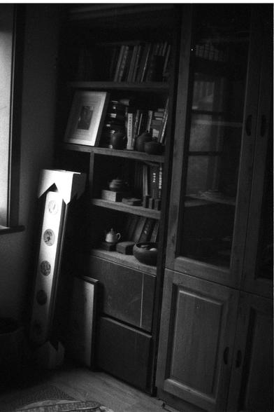 Ilford FP4 Plus 125 (FF)

🇬🇧 English Alt Text

A monochrome photograph showing a wooden bookshelf packed with assorted items—books, teapots, and framed pictures. A tall, slim box decorated with circular designs leans against the shelf. The dim lighting gives the space a quiet, nostalgic feel.

🇨🇳 中文替代文本

一张黑白照片，展示了一个木质书架，书架上摆满了书籍、茶壶和装裱的照片等物品。一个带有圆形图案的高窄盒子倚靠在书架旁。昏暗的灯光营造出安静而怀旧的氛围。