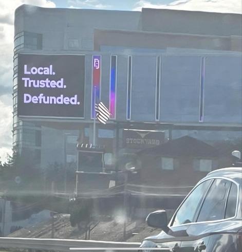 Photo of the building housing the PBS station in Boston, WGBH. 
A big sign says,
LOCAL.
TRUSTED.
DEFUNDED.